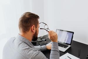 Homme avec lunettes  regarde son ordinateur