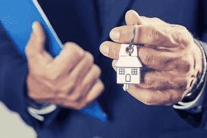 Homme tenant une clé de maison et une pochette bleue dans la main