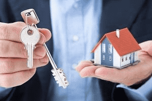 personne qui tient une clé de maison et une maquette de maison